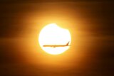 An aeroplane flies past the sun as it goes into a partial solar eclipse in Singapore.