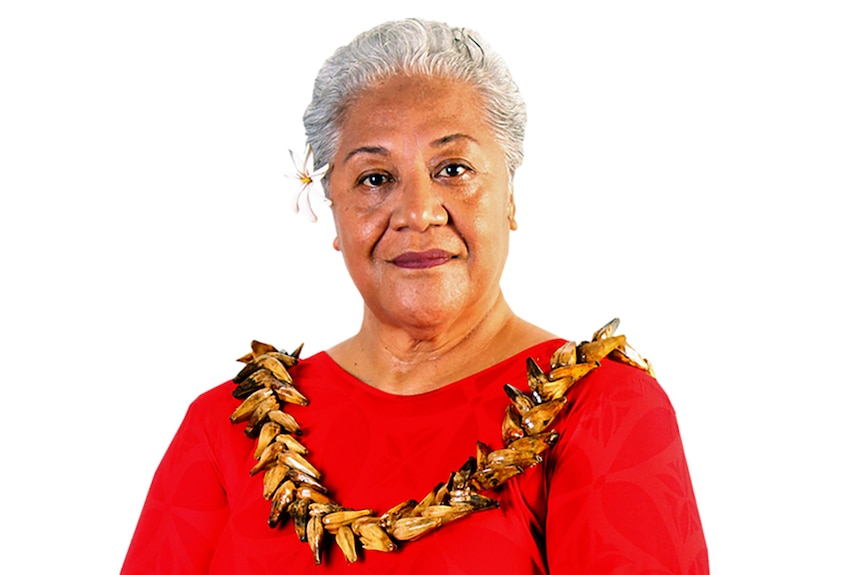 Fiame Naomi Mata'afa poses for a portrait with a red dress, flower in her hair an traditional garland.