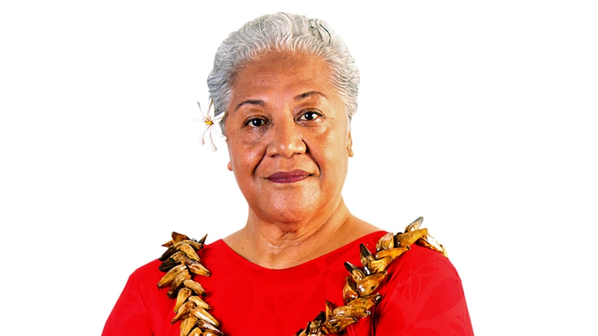 Fiame Naomi Mata'afa poses for a portrait with a red dress, flower in her hair an traditional garland.