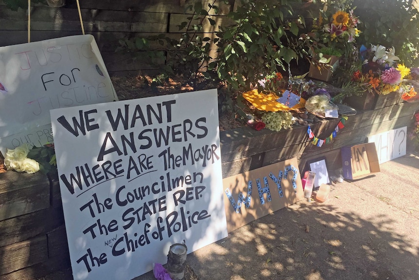 Signs and flowers at a memorial for Justine Damond