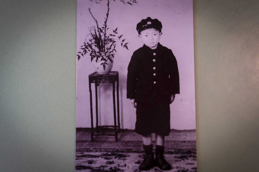 An old photo of a young Japanese boy in a coat and cap
