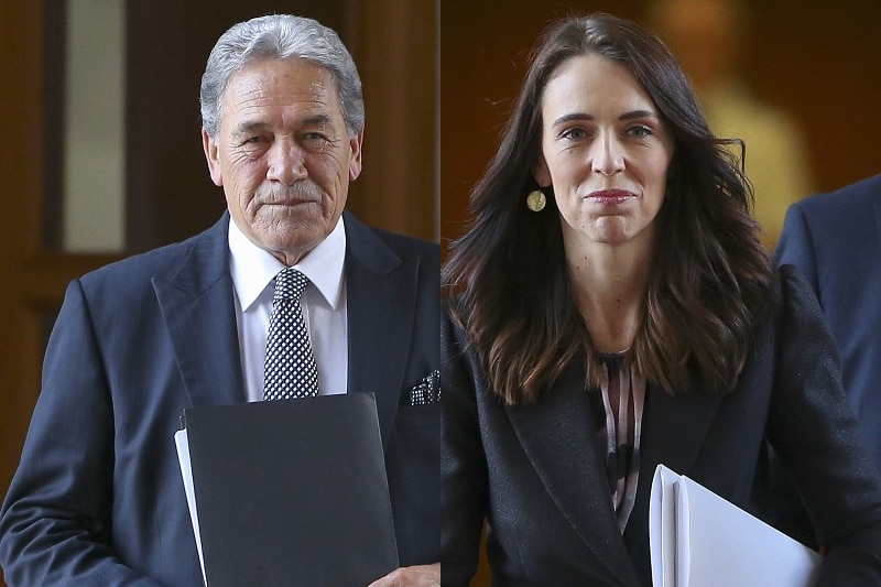 Jacinda Ardern walks with Winston Peters, both clutching papers and staring ahead.