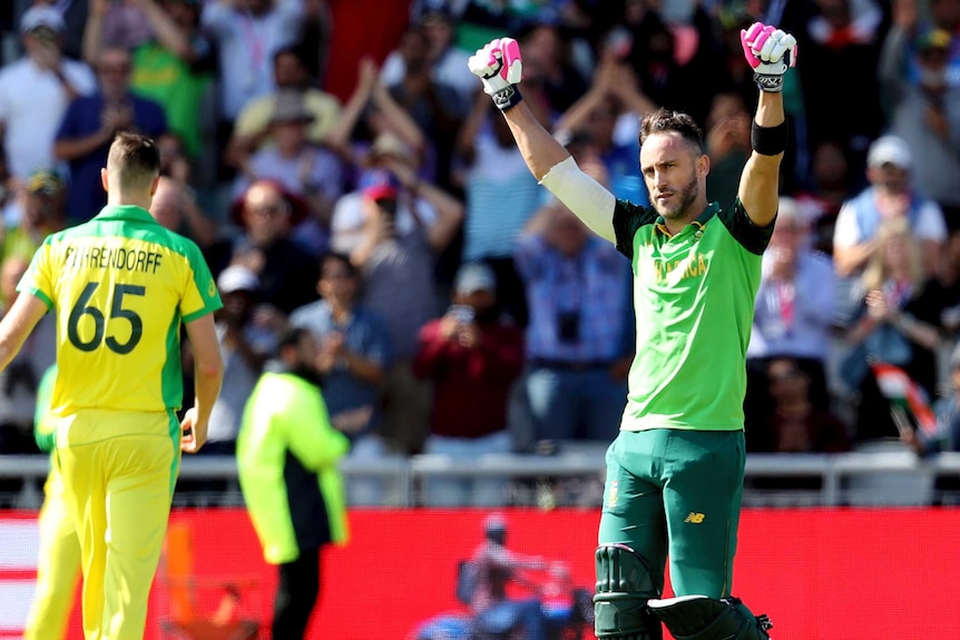 South Africa batsman Faf du Plessis raises both fists after scoring a Cricket World Cup century. Jason Behrendorff walks away.