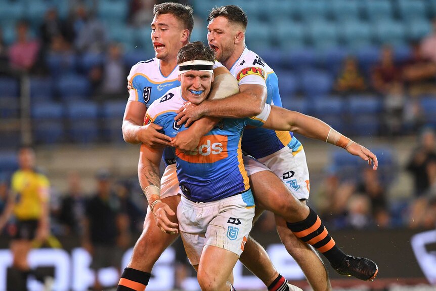 Three NRL teammates celebrate, with two jumping on the try-scorer.