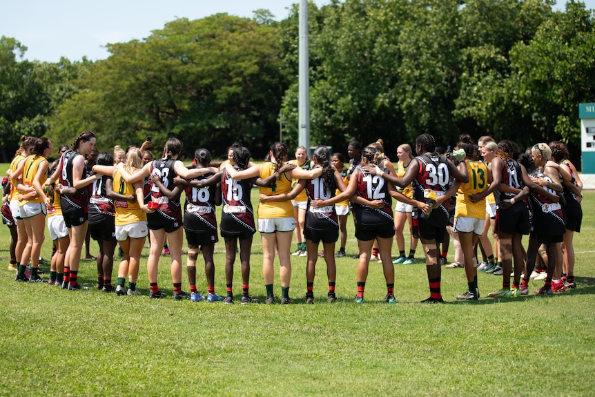 A female AFL coach points, while in front of a white board. 