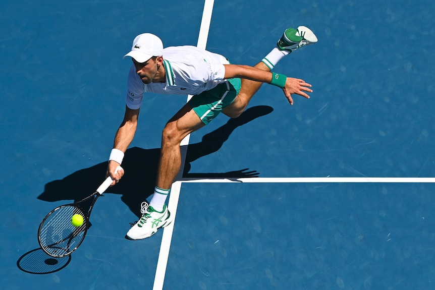Novak Djokovic is at full stretch and reaching down for a low forehand
