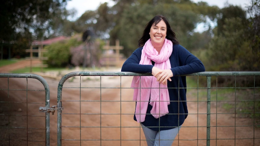 A woman leaning on a fence 