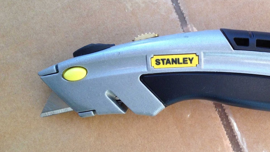 A retractable knife on a cardboard box.