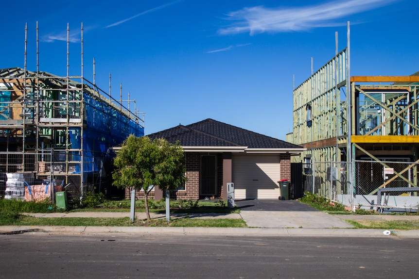 A new, single-storey home sits between two two-storey homes under construction.