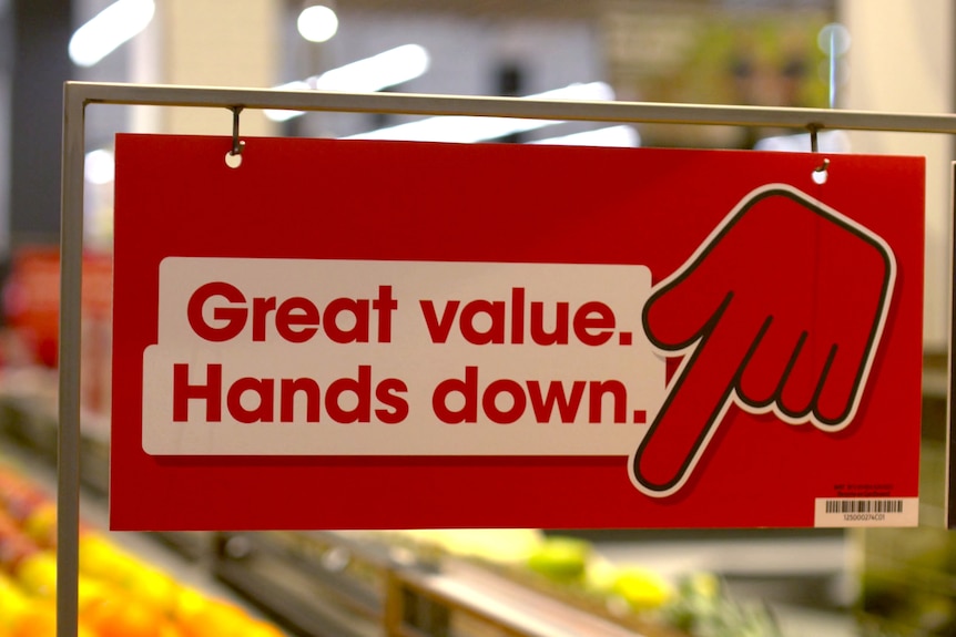 A sign in a Coles fresh produce section saying 'Great Value. Hands down' with a red hand pointing down.