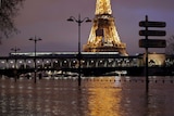 A photo taken at night time shows the Eiffel Tower lit up and surrounded by floodwaters