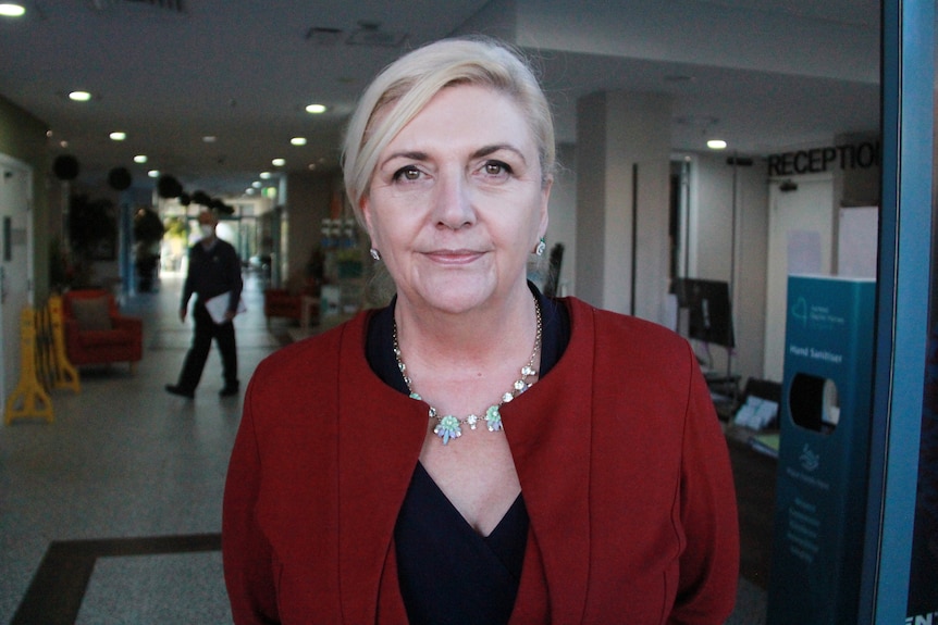 a woman standing inside an aged care centre looking at the camera