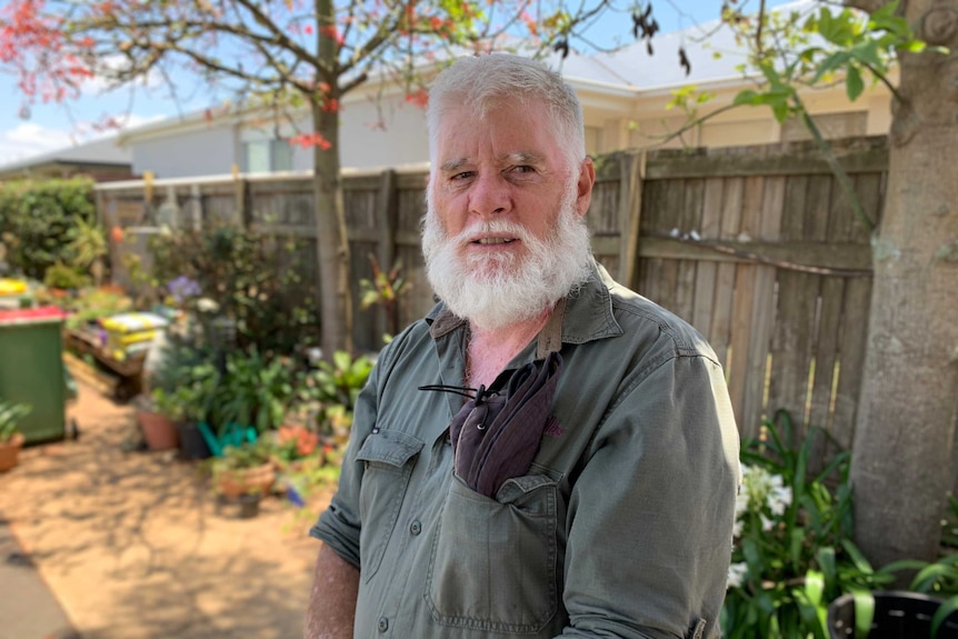 A man stands in front of a fence