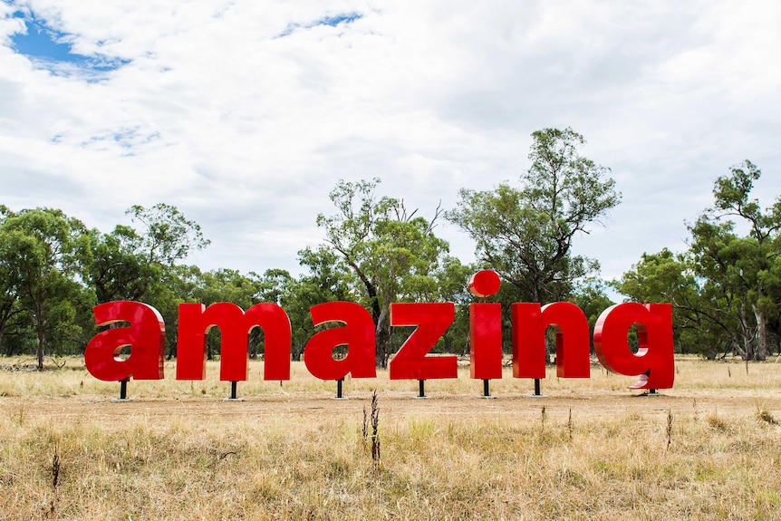 Red letters spelling the word Amazing form a sculpture in a paddock