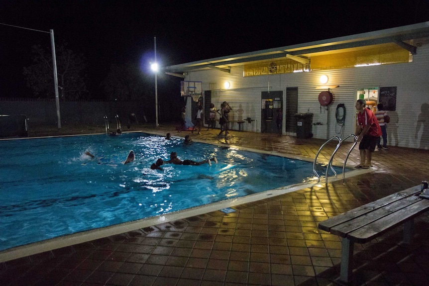 Children swim in Fitzroy Crossing's public pool at night.
