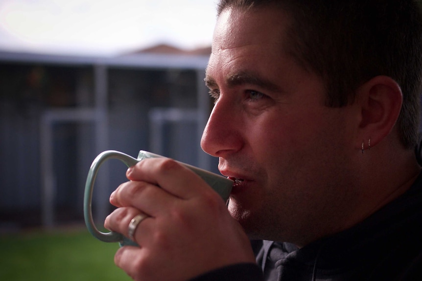 A man drinks for a blue mug.