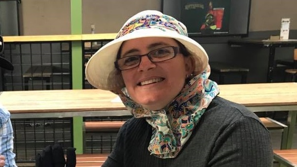 A smiling woman wearing a bonnet and glasses.