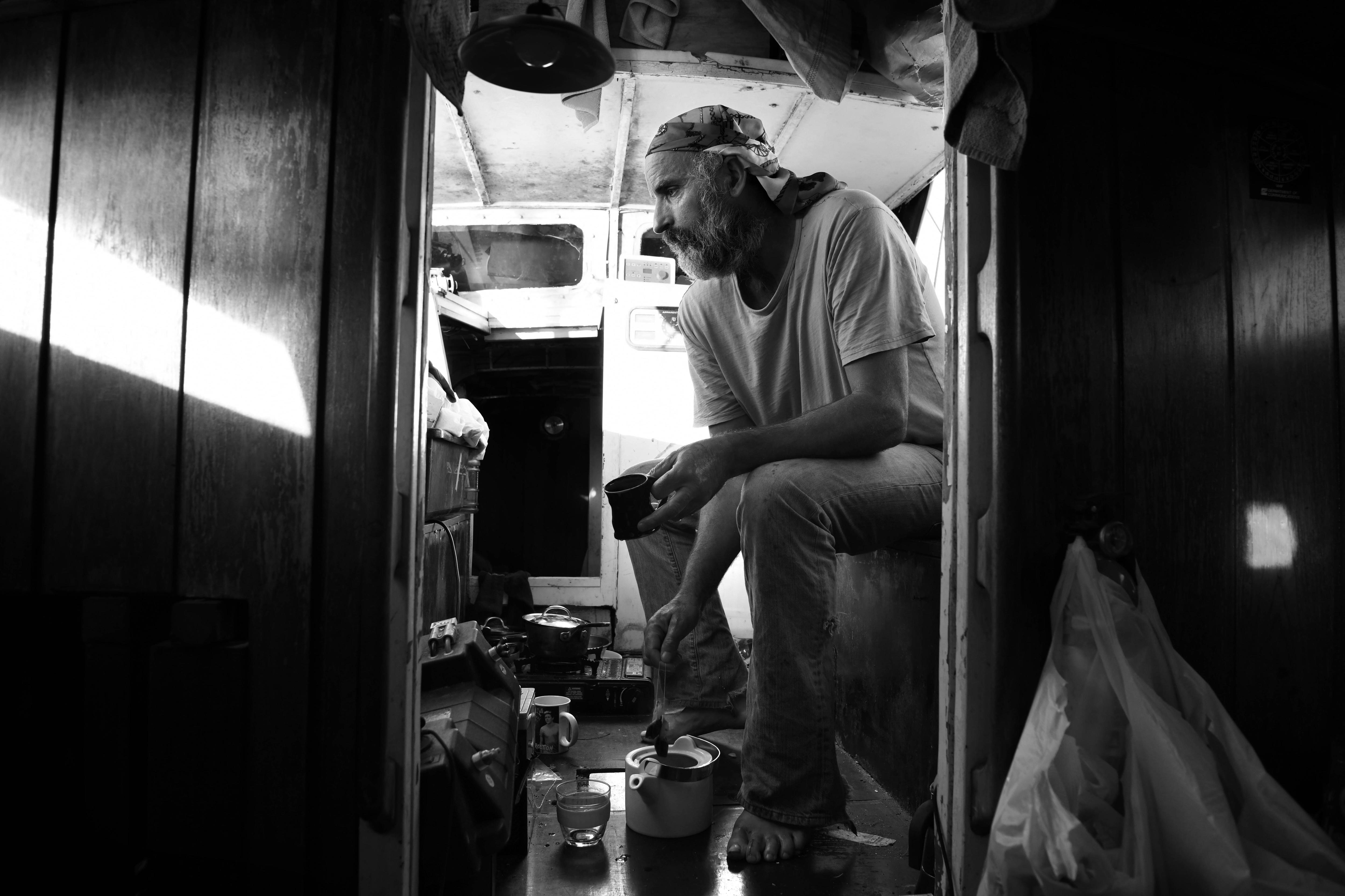 A man wearing a bandanna places his teapot on the floor