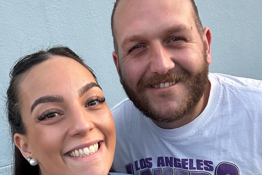 A man and a woman smiling and taking a selfie photo. 