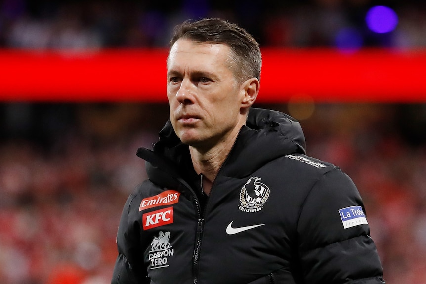 Collingwood AFL coach Craig McRae looks sad as he stands on the ground after a finals loss. 