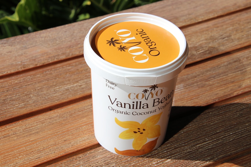 a tub of coyo yogburt sitting on a bench in the sun