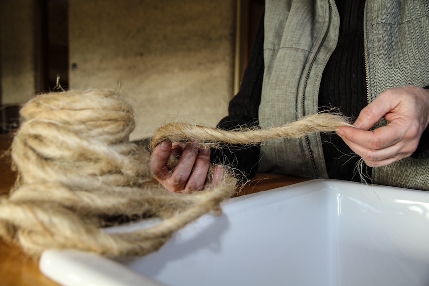 Lyn Stephenson's hands holding plumbers tape made from hemp fibre.