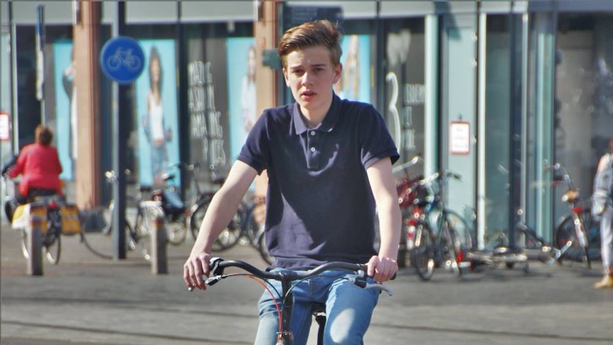Teenage rides his bike wearing no helmet