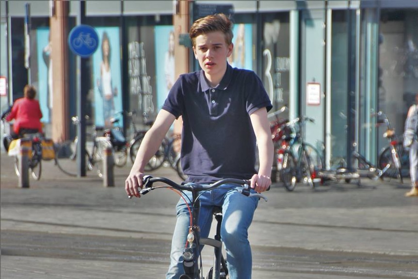 Teenage rides his bike wearing no helmet
