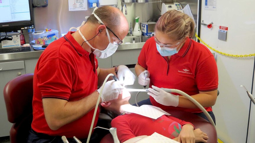 Dr Ian Odendaal, left, principal dentist with the Royal Flying Doctor Service, works on a patient.