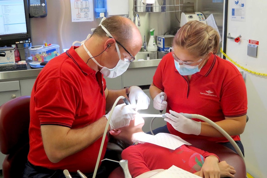 Dr Ian Odendaal, left, principal dentist with the Royal Flying Doctor Service, works on a patient.