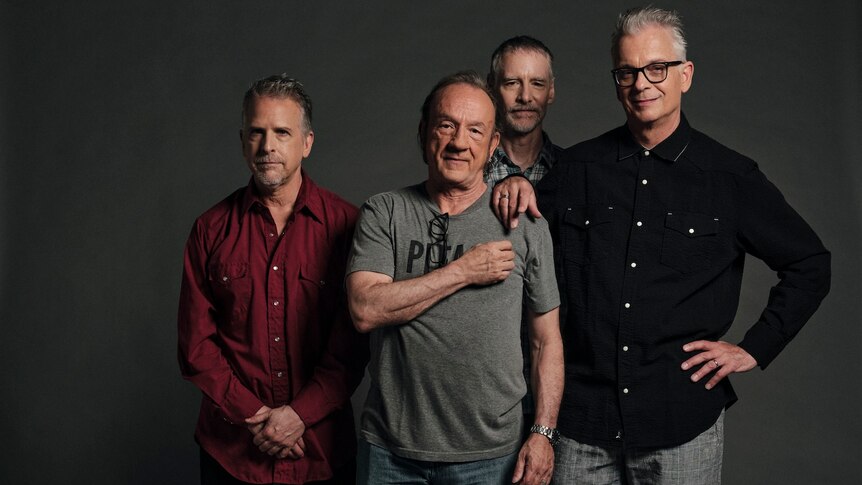Press photo for American rock group The Jesus Lizard shows four older men standing in front of a grey background