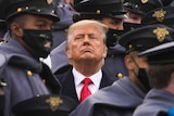 President Donald Trump is seen surrounded by army cadets in uniform.