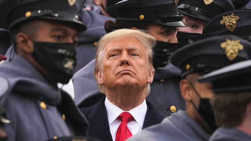 President Donald Trump is seen surrounded by army cadets in uniform.
