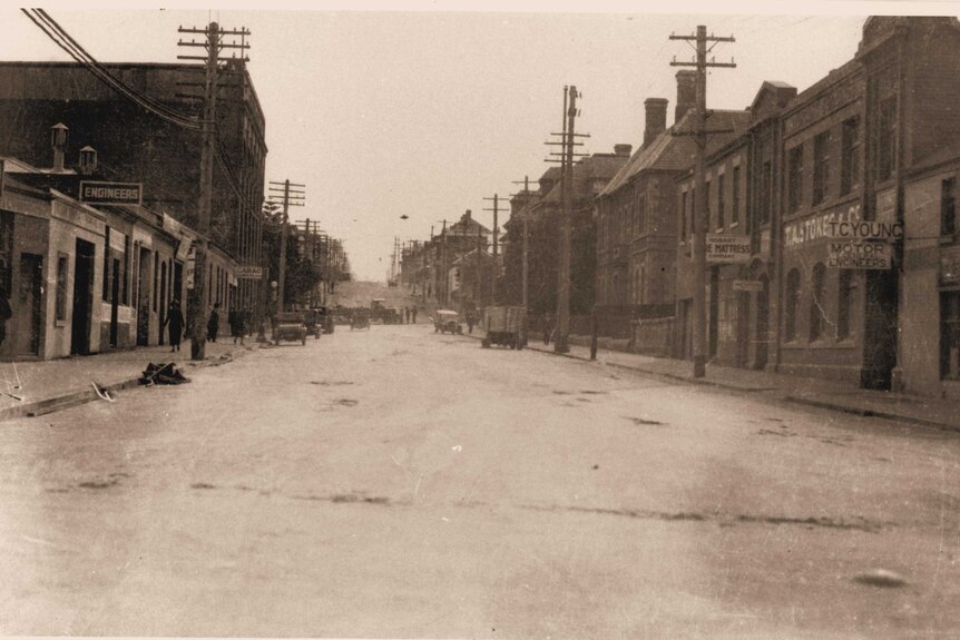 Sepia-coloured photo of a wide street with wooden power poles on the sides