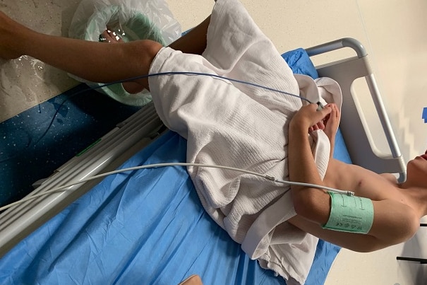 Young boy sitting on hospital bed with blood pressure pump on