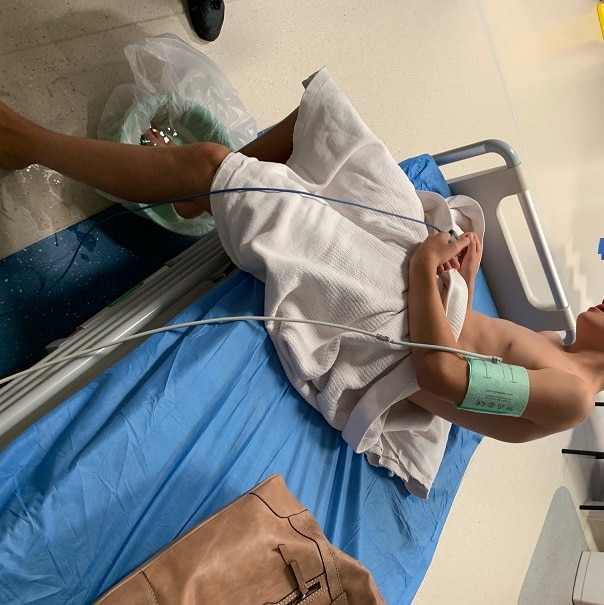 Young boy sitting on hospital bed with blood pressure pump on