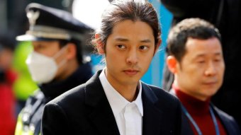 Man-bunned K-Pop star Jung Joon-young arrives for questioning by police.