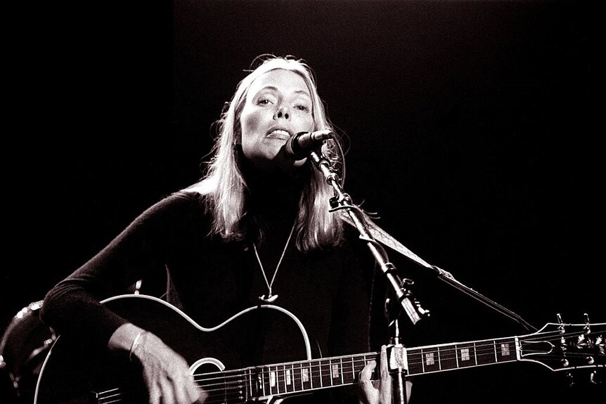 Joni Mitchell performing on acoustic guitar