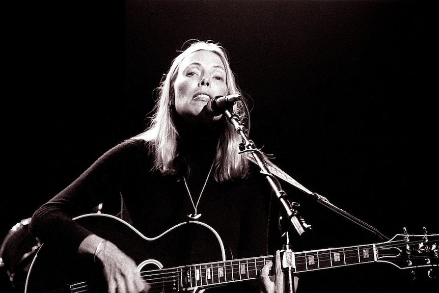 Joni Mitchell performing on acoustic guitar