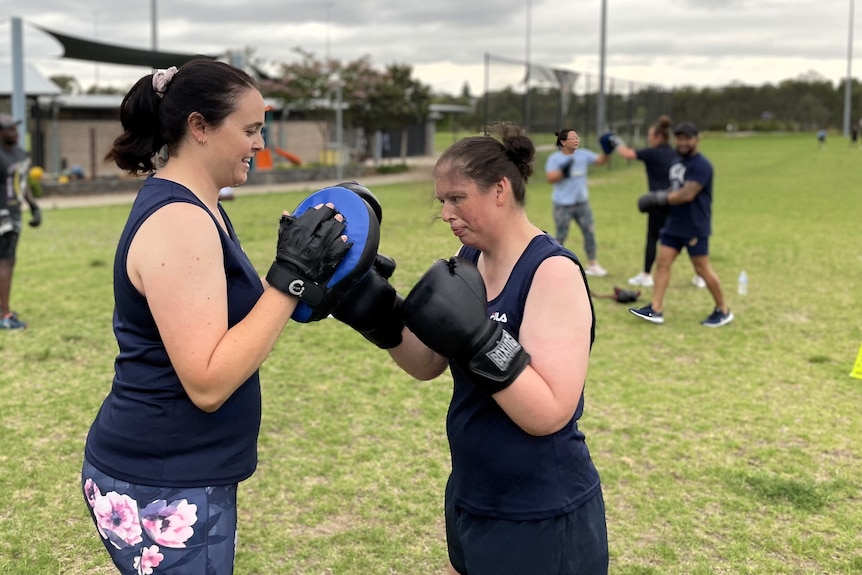 Two women sparring boxing in a park.