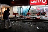 A man walks in front of a convenience store damaged by the earthquake.