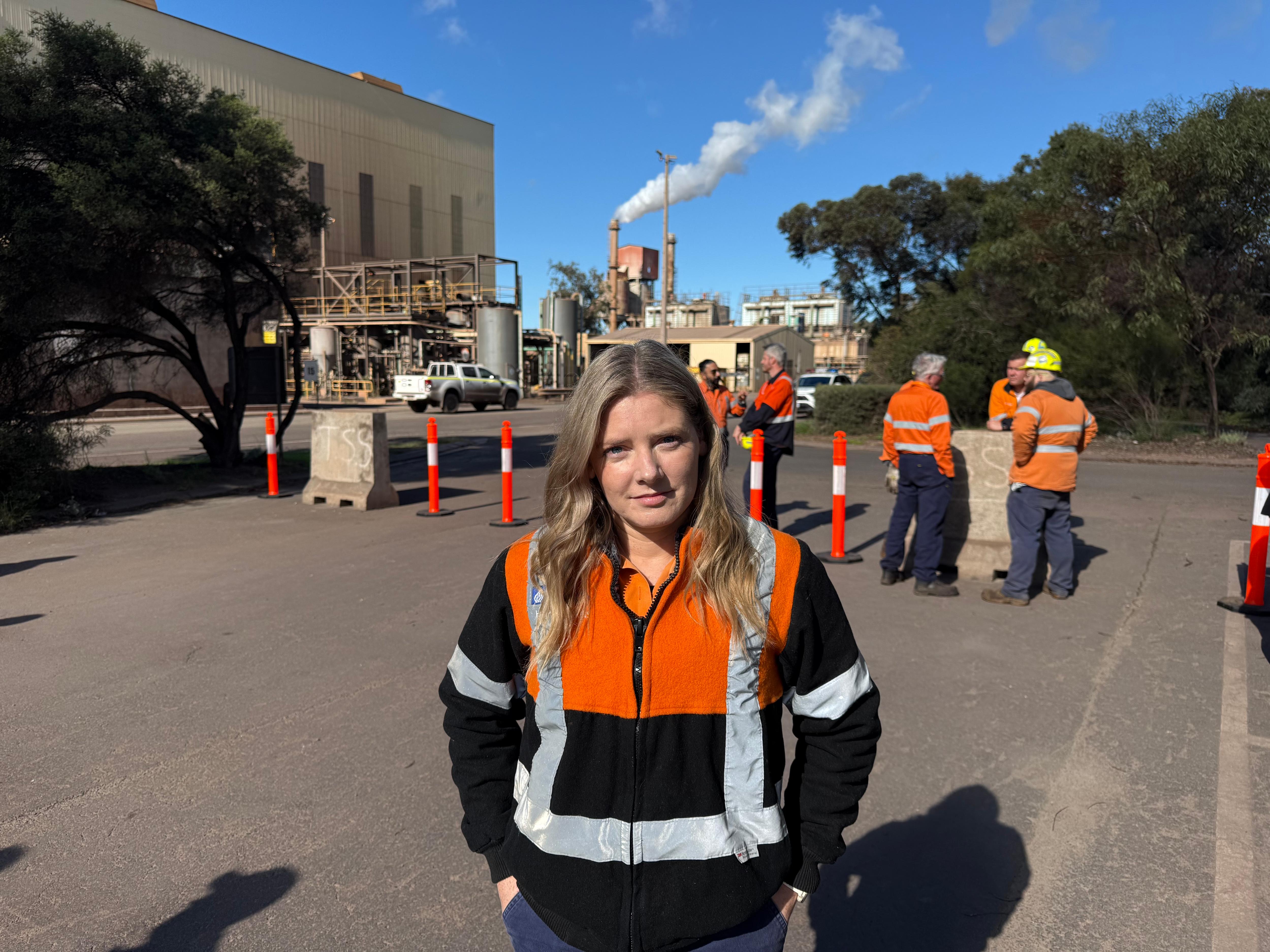 Una mujer con una chaqueta naranja y azul en un sitio industrial