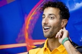 Daniel Ricciardo holds a finger to his ear to listen to a reporter during a press conference before the F1 Belgian Grand Prix.