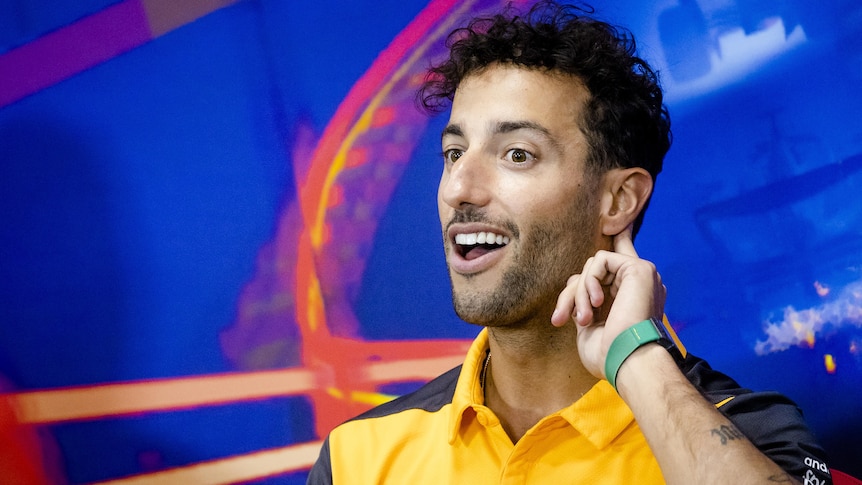 Daniel Ricciardo holds a finger to his ear to listen to a reporter during a press conference before the F1 Belgian Grand Prix.