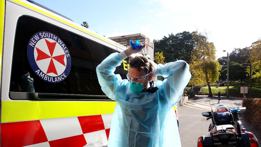 An ambulance worker is pictured in PPE preparing to transport a suspected COVID patient to St Vincent's Hospital in Sydney.