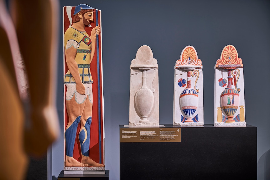 An ancient greek soldier in profile and painted in vivid colours, three identical Greek vases with increasing colours painted on
