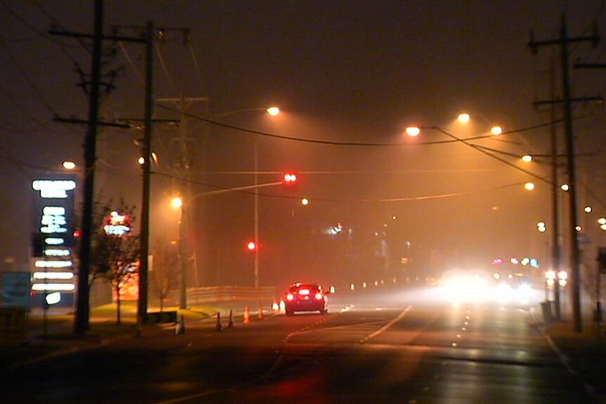 A dark, smoky street at night time.