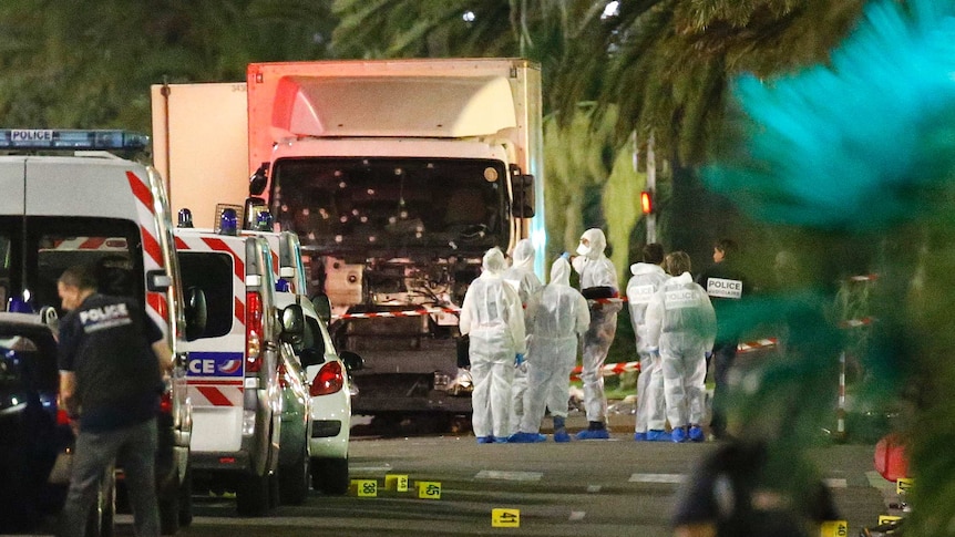 Police stand next to a truck that ran into a crowd celebrating Bastille Day.