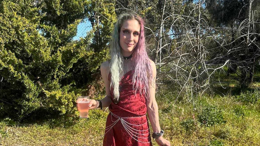 A woman wearing a red dress holding a glass of beer poses for the camera