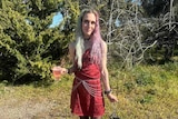 A woman wearing a red dress holding a glass of beer poses for the camera